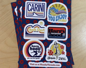 May include: A set of six colorful stickers featuring various designs, including a surfer, a hula dancer, and a logo with the text "Harry Hood 85". The stickers are printed on white paper and have a blue background with red polka dots.