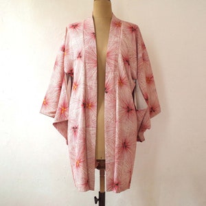 May include: A pink and white kimono with a floral pattern. The kimono is made of a soft, lightweight fabric and has a relaxed fit.