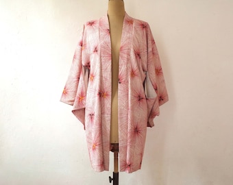 Puede incluir: Un kimono rosa y blanco con un estampado floral. El kimono está hecho de una tela suave y ligera y tiene un corte holgado.