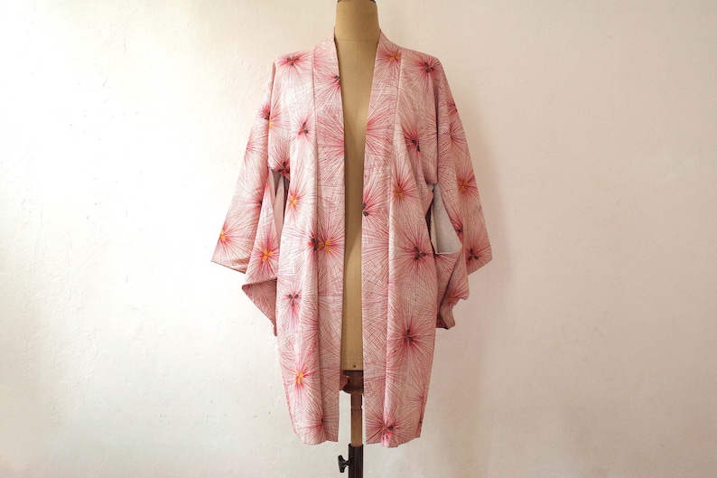 May include: A pink and white kimono with a floral pattern. The kimono is made of a soft, lightweight fabric and has a relaxed fit.