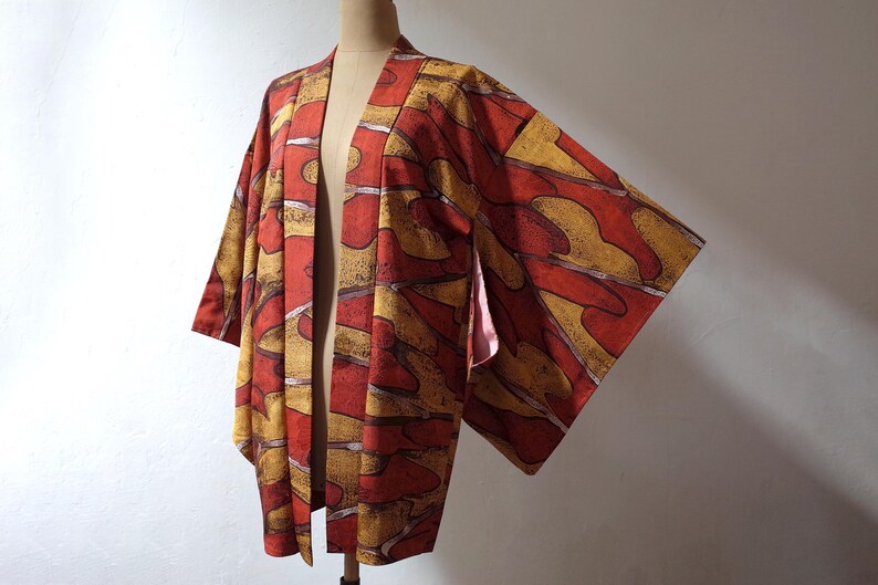 May include: A red and gold patterned Japanese kimono with a long sleeve design.