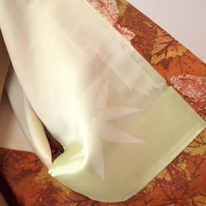 May include: A close-up of a light brown and orange fabric with a pattern of leaves and a light green lining. The lining has a subtle embossed design.