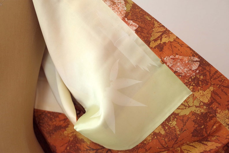 May include: A close-up of a light brown and orange fabric with a pattern of leaves and a light green lining. The lining has a subtle embossed design.
