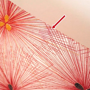 May include: Close-up of a red and white fabric with a geometric pattern. The fabric has a grid pattern with red lines and a white background. The fabric is textured and has a slight sheen.