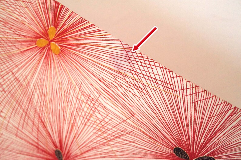 May include: Close-up of a red and white fabric with a geometric pattern. The fabric has a grid pattern with red lines and a white background. The fabric is textured and has a slight sheen.