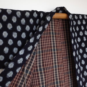 May include: A black and white reversible kimono with a polka dot pattern on one side and a plaid pattern on the other side.