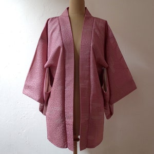 Puede incluir: Un kimono japon&eacute;s rosa con un patr&oacute;n geom&eacute;trico blanco. El kimono est&aacute; hecho de una tela suave y ligera y tiene un corte holgado.