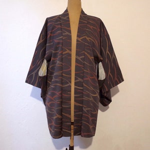 May include: A dark gray kimono with a brown and orange abstract pattern. The kimono has long sleeves and a wide collar.