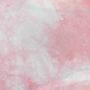 May include: A pink and white tie-dye fabric with a soft, textured surface.