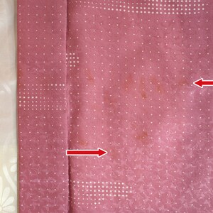 Puede incluir: Una tela rosa con un patr&oacute;n de lunares blancos. Hay dos manchas marrones en la tela.