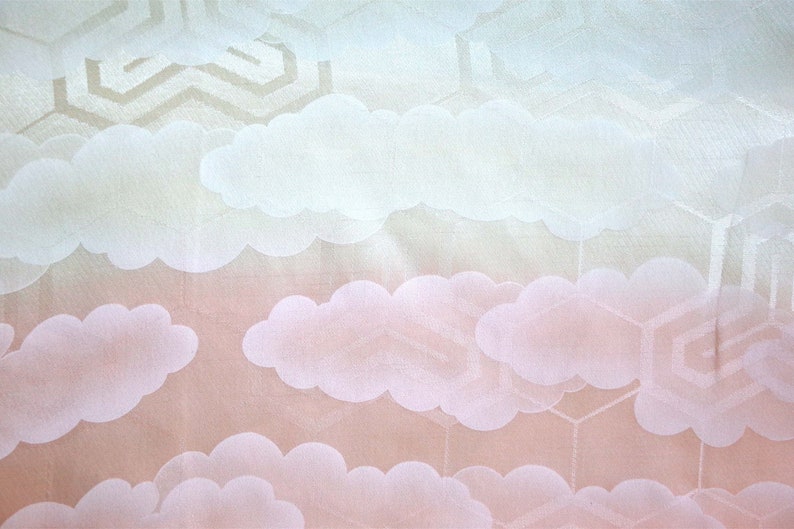 K&ouml;nnte beinhalten: Ein wei&szlig;er Stoff mit einem dezenten Muster aus Wolken und geometrischen Formen. Der Stoff hat einen Farbverlauf von Hellblau zu Rosa.