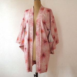May include: A pink and white kimono with a floral pattern. The kimono has a long, flowing silhouette and is made of a lightweight fabric.