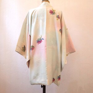 K&ouml;nnte beinhalten: Ein hellgr&uuml;nes und rosa japanisches Kimono mit Blumenstickerei. Das Kimono hat ein traditionelles Design und ist aus einem weichen, flie&szlig;enden Stoff gefertigt.