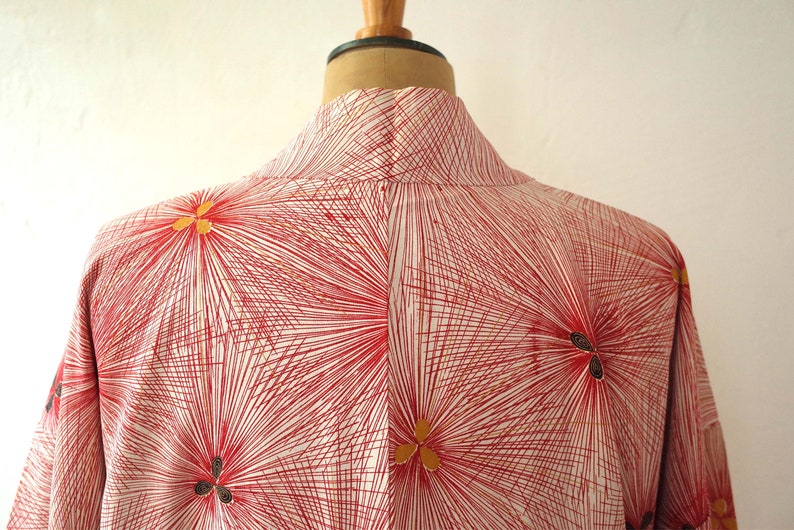 May include: A red and white kimono with a geometric pattern of radiating lines and gold flower accents.