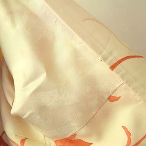 Puede incluir: Un kimono blanco con un delicado estampado floral en tonos naranja. El kimono est&aacute; hecho de una tela suave y sedosa y tiene un dise&ntilde;o japon&eacute;s tradicional.