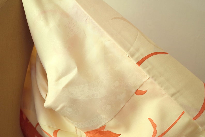 Puede incluir: Un kimono blanco con un delicado estampado floral en tonos naranja. El kimono est&aacute; hecho de una tela suave y sedosa y tiene un dise&ntilde;o japon&eacute;s tradicional.