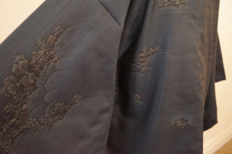 Op de afbeelding: Een donkerblauwe kimono met een subtiel patroon van zwarte en zilveren wolken en bomen.