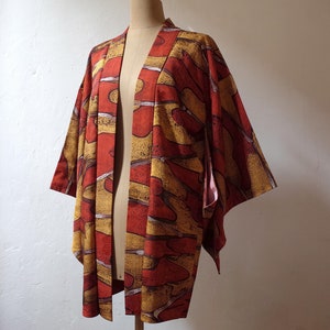 May include: A red and yellow patterned kimono with a long sleeve design. The kimono is made of a soft, lightweight fabric and has a relaxed fit.