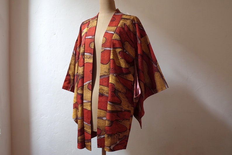 May include: A red and yellow patterned kimono with a long sleeve design. The kimono is made of a soft, lightweight fabric and has a relaxed fit.