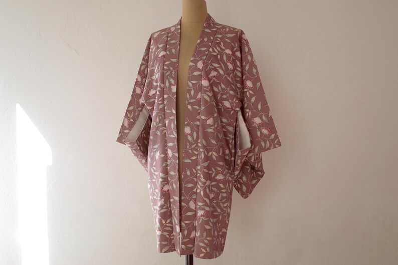 May include: A mauve kimono with a floral pattern of pink flowers and green leaves.