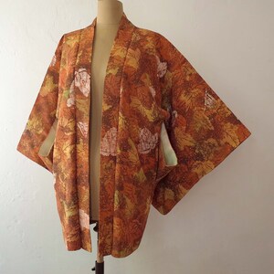 May include: A brown and orange kimono with a floral pattern. The kimono has a green and white lining.