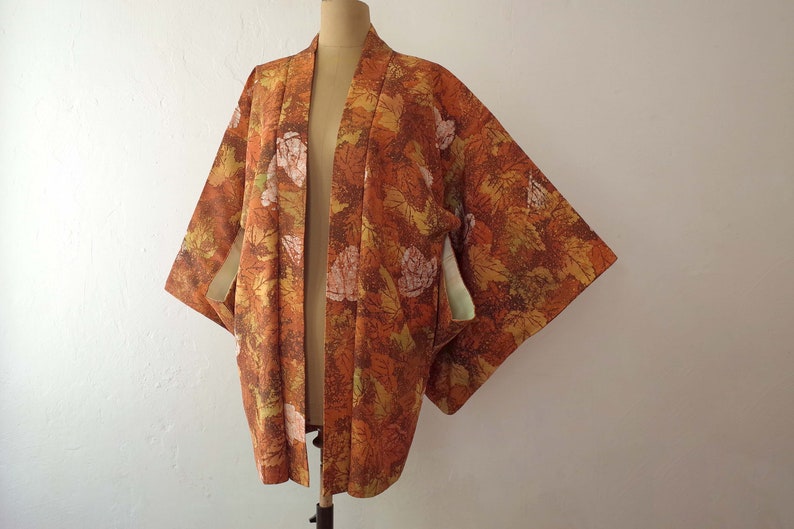 May include: A brown and orange kimono with a floral pattern. The kimono has a green and white lining.