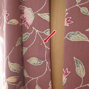 May include: A close-up of a pink fabric with a floral pattern. The fabric has a small brown stain on it.