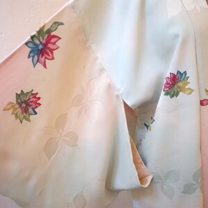 K&ouml;nnte beinhalten: Ein hellblaues und rosafarbenes Kimono mit Blumenmuster. Das Kimono hat ein rosafarbenes Futter und ist aus einem weichen, seidigen Stoff gefertigt.