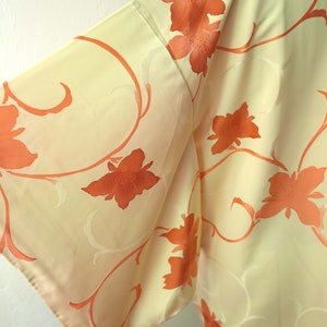 Puede incluir: Un kimono de color crema con un patr&oacute;n floral en tonos naranja. El kimono est&aacute; hecho de una tela suave y sedosa y presenta un dise&ntilde;o japon&eacute;s tradicional.