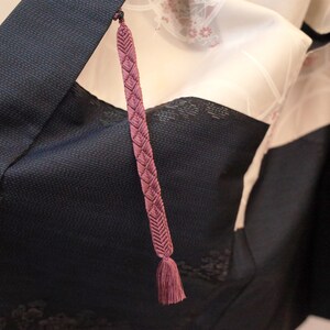 Op de afbeelding: Een close-up van een donkerblauwe kimono met een roze kwast die aan de kraag hangt.