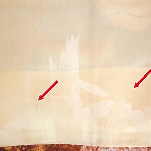 May include: A close-up of a light beige fabric with two white stains. The stains are highlighted with red arrows.