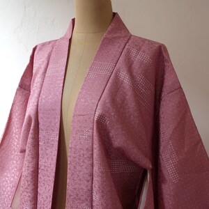Puede incluir: Un kimono japon&eacute;s rosa con un dise&ntilde;o estampado blanco. El kimono est&aacute; hecho de una tela suave y sedosa y tiene un estilo tradicional.