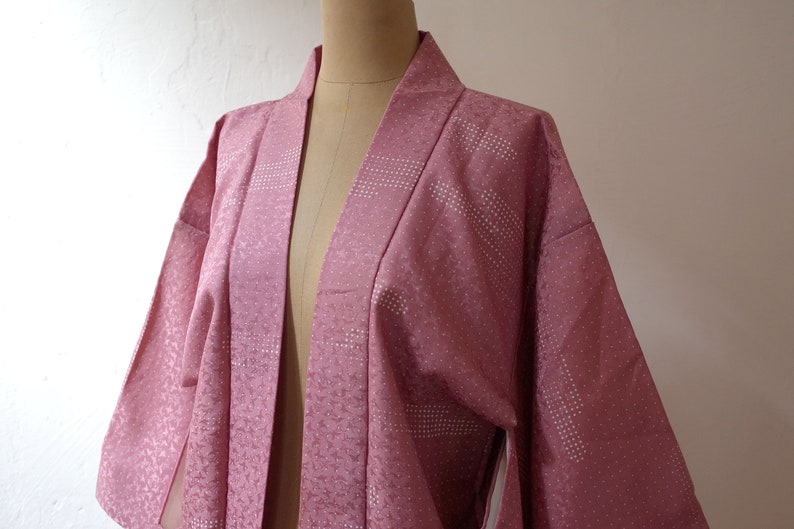 Puede incluir: Un kimono japon&eacute;s rosa con un dise&ntilde;o estampado blanco. El kimono est&aacute; hecho de una tela suave y sedosa y tiene un estilo tradicional.