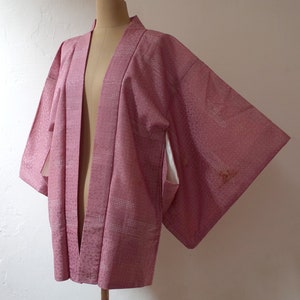 Puede incluir: Un kimono japon&eacute;s de color rosa y blanco con un forro blanco. El kimono est&aacute; abierto por delante y tiene mangas largas.