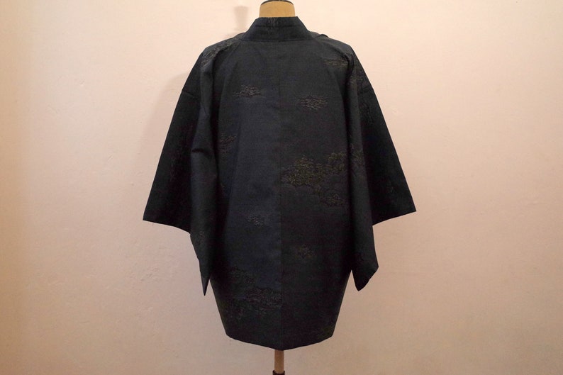 Op de afbeelding: Een donkerblauwe kimono met een subtiel patroon van gouden bladeren. De kimono is gemaakt van een zachte, zijdeachtige stof en heeft een traditioneel Japans ontwerp.