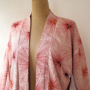 May include: A white kimono with a red and gold floral pattern. The kimono is open in the front and has long sleeves.