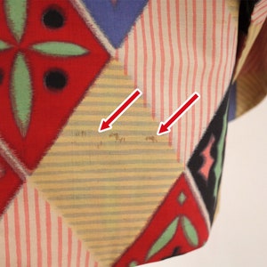 May include: A yellow, red, and blue patterned fabric with a geometric design. The fabric has some light brown stains.