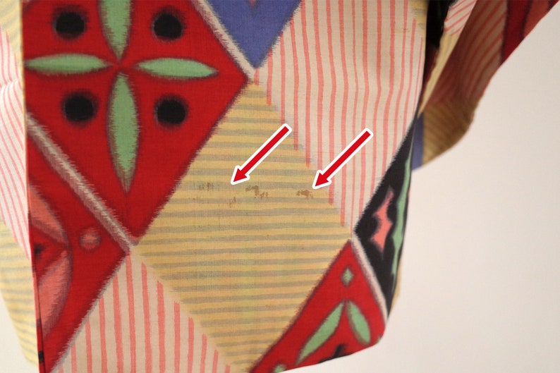 May include: A yellow, red, and blue patterned fabric with a geometric design. The fabric has some light brown stains.