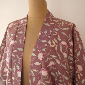 May include: A mauve kimono with a floral pattern of pink flowers and green leaves.