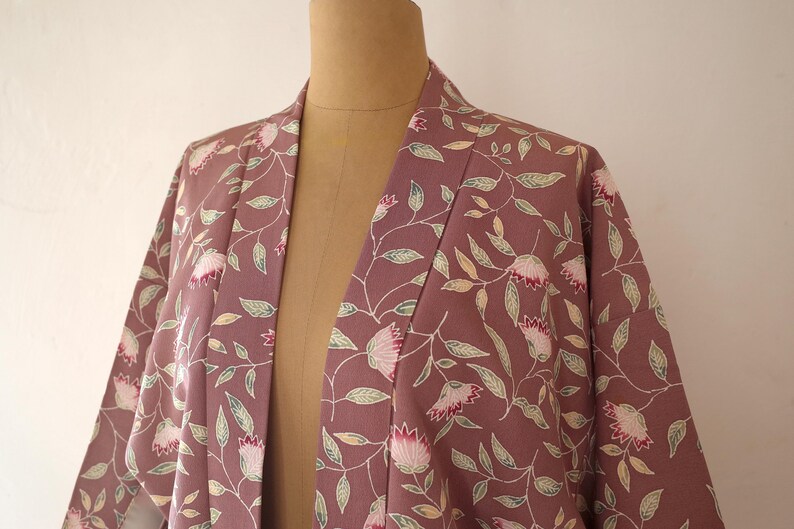 May include: A mauve kimono with a floral pattern of pink flowers and green leaves.