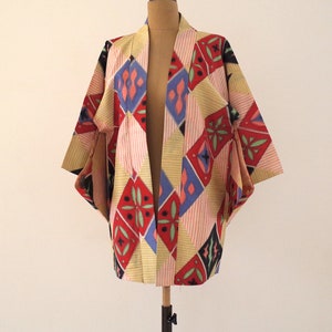 May include: A colorful kimono with a geometric pattern in shades of red, blue, yellow, and black. The kimono is made of a lightweight fabric and has a relaxed fit.
