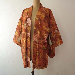 May include: A brown and orange kimono with a leaf pattern. The kimono is open in the front and has a long, flowing silhouette.