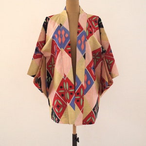 May include: A colorful kimono with a geometric pattern in shades of red, blue, yellow, and green. The kimono is made of a lightweight fabric and has a relaxed fit.