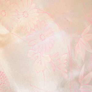 May include: A white fabric with a pink floral pattern. The flowers are stylized and have a delicate, almost faded appearance.