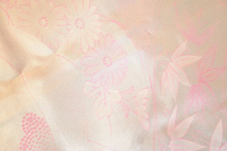 May include: A white fabric with a pink floral pattern. The flowers are stylized and have a delicate, almost faded appearance.