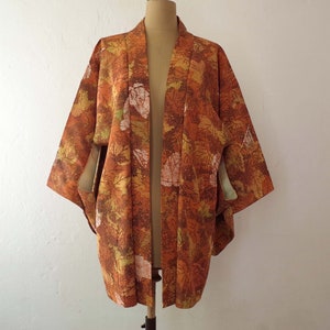 May include: A brown and orange kimono with a leaf pattern. The kimono is open in the front and has long sleeves.