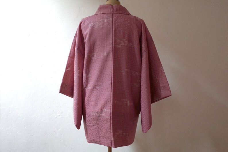 Puede incluir: Un Hanten japon&eacute;s rosa, una chaqueta tradicional corta y sin forro, con un patr&oacute;n geom&eacute;trico blanco.