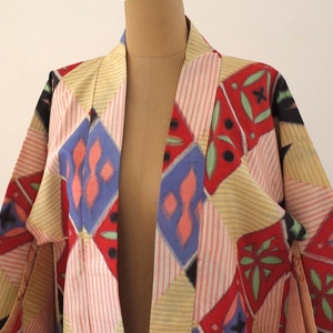 May include: A colorful kimono with a geometric pattern in shades of red, blue, yellow, and green. The kimono is made of a lightweight fabric and has a relaxed fit.
