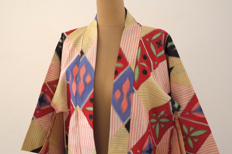 May include: A colorful kimono with a geometric pattern in shades of red, blue, yellow, and green. The kimono is made of a lightweight fabric and has a relaxed fit.