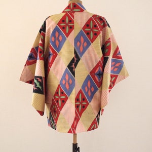 May include: A traditional Japanese haori jacket with a colorful geometric pattern in shades of red, blue, yellow, and black. The haori is made of a lightweight fabric and has a relaxed fit.